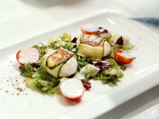 Il nostro hotel a 3 stelle in Val Gardena e la sua cucina Insalata fresca con zucchine grigliate e pomodori su piatto bianco