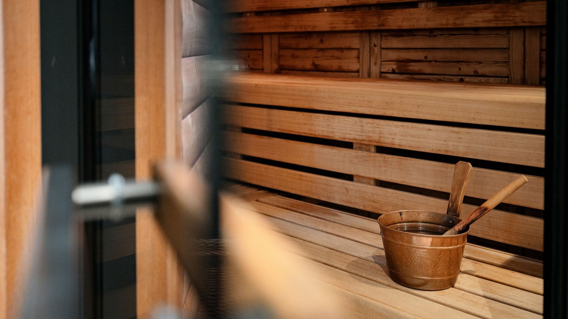 Hotel a Santa Cristina in Val Gardena con piscina: relax puro Interno di una sauna con panche in legno e secchio di legno
