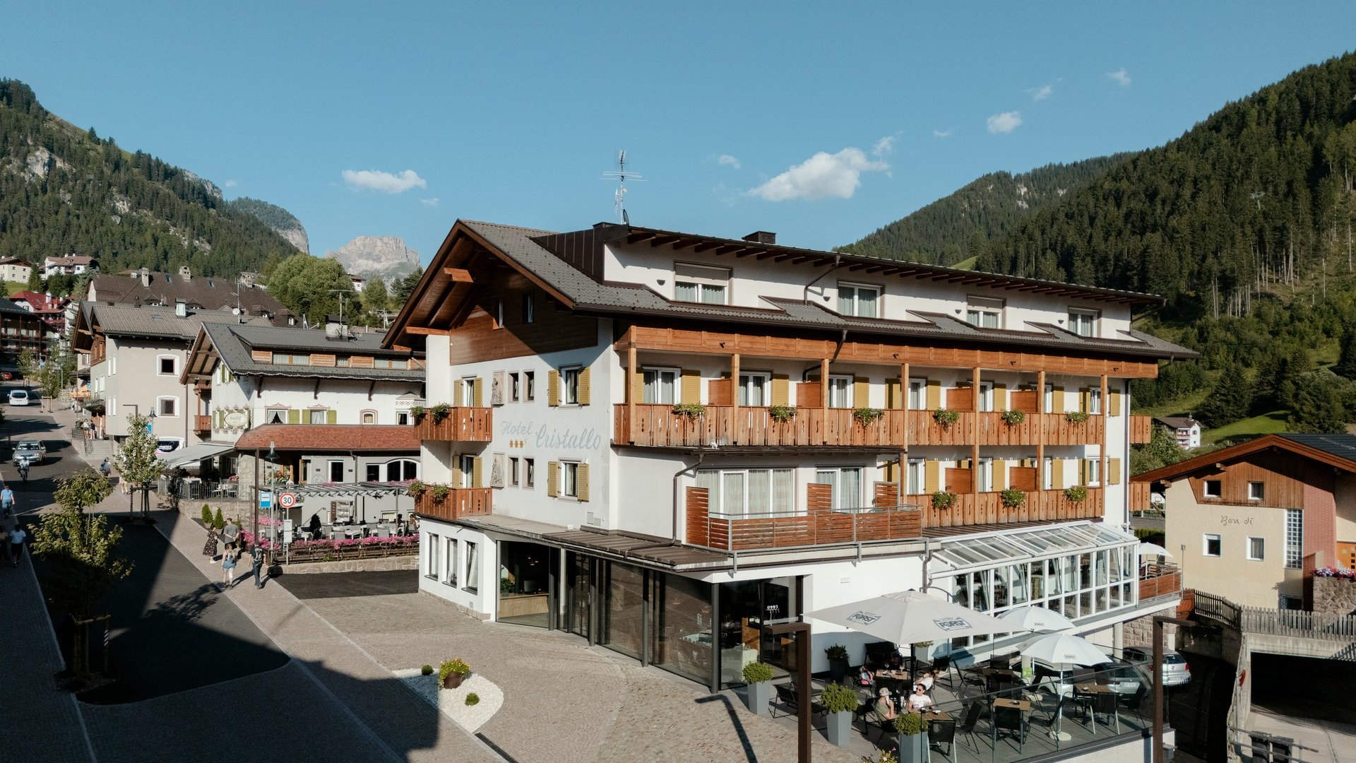 Deine Unterkunft in St. Christina im Grödnertal: Willkommen! Hotel mit Balkonterrasse und umliegenden Bergen an einem sonnigen Tag