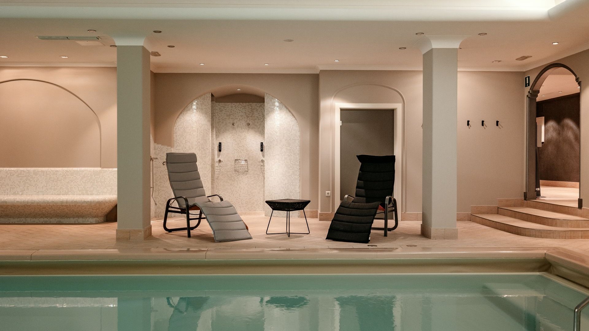 Hotel a Santa Cristina in Val Gardena con piscina: relax puro Piscina interna con sedie a sdraio, doccia e area salotto in una stanza luminosa