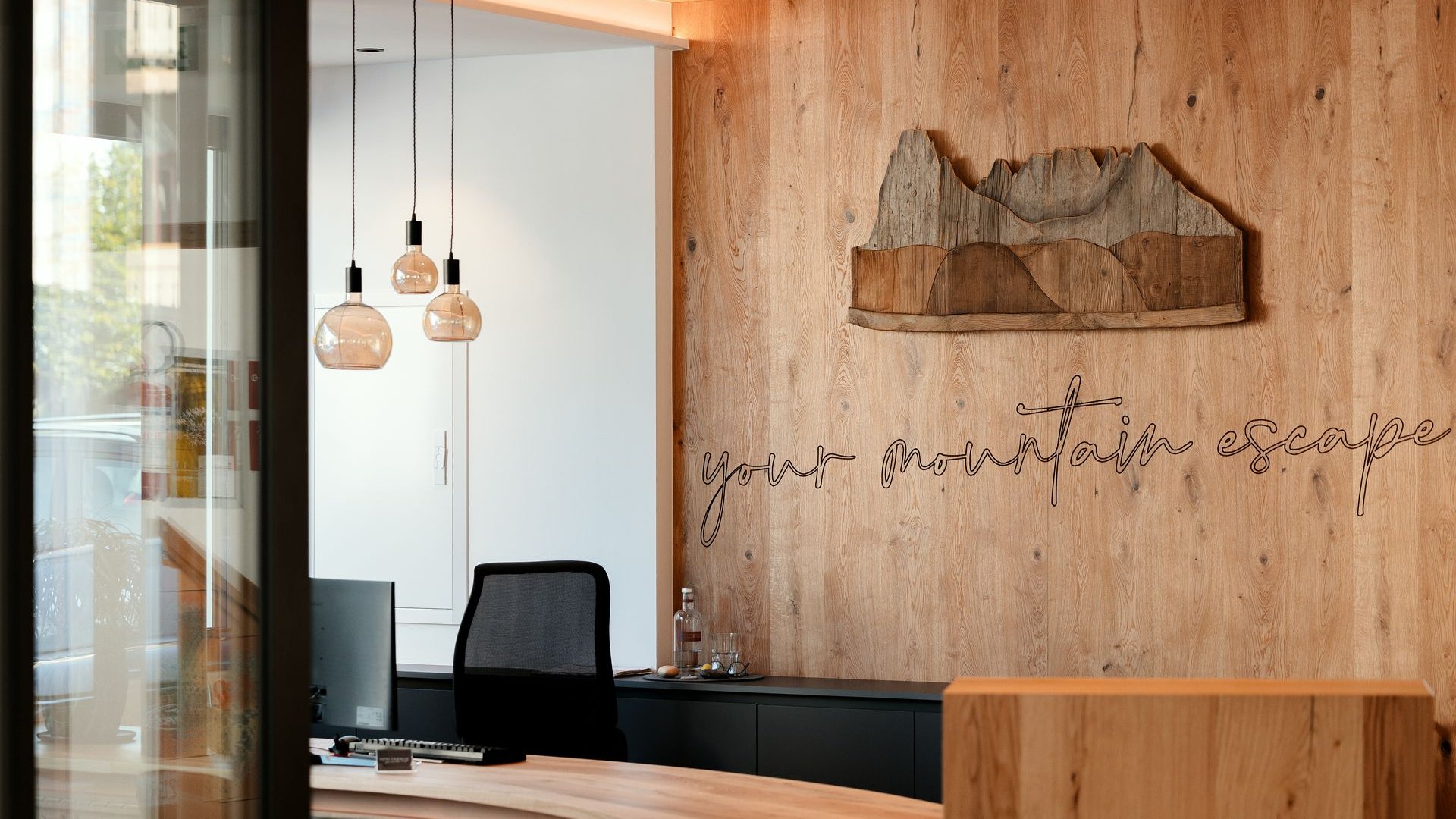 Hotel a Santa Cristina in Val Gardena: your mountain escape Reception moderna in legno con decorazione montagna e scritta your mountain escape