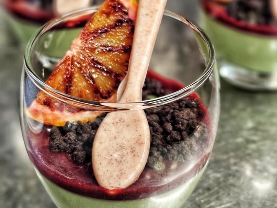 Il nostro hotel a 3 stelle in Val Gardena e la sua cucina Bicchiere di dessert con budino verde, salsa rossa, pezzetti di cioccolato e fetta d'arancia