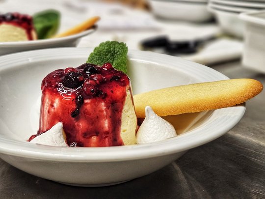 Il nostro hotel a 3 stelle in Val Gardena e la sua cucina Dessert con salsa di frutti di bosco, menta, meringa e biscotto su piatto bianco