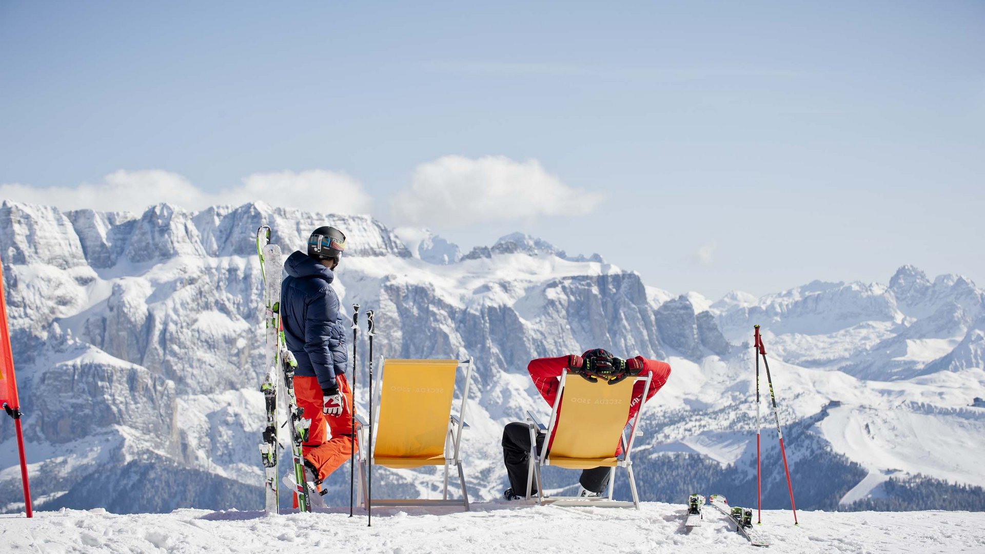 Deine Unterkunft in St. Christina im Grödnertal: Willkommen! Skifahrer entspannen auf Liegestühlen mit Blick auf verschneite Berge