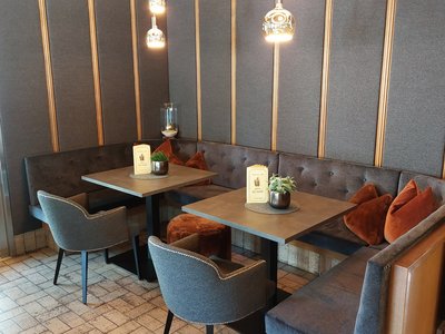 Deine Unterkunft in St. Christina im Grödnertal: Willkommen! Gemütliche Sitzecke mit Tischen, Stühlen und braunen Kissen in Restaurant