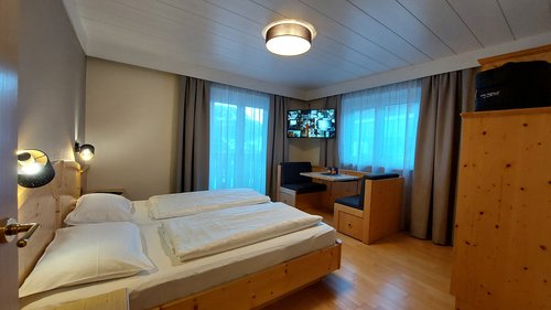 Hotel a 3 stelle a Santa Cristina: per un benessere stellare Camera d'hotel accogliente con letto matrimoniale, angolo salotto e TV a parete