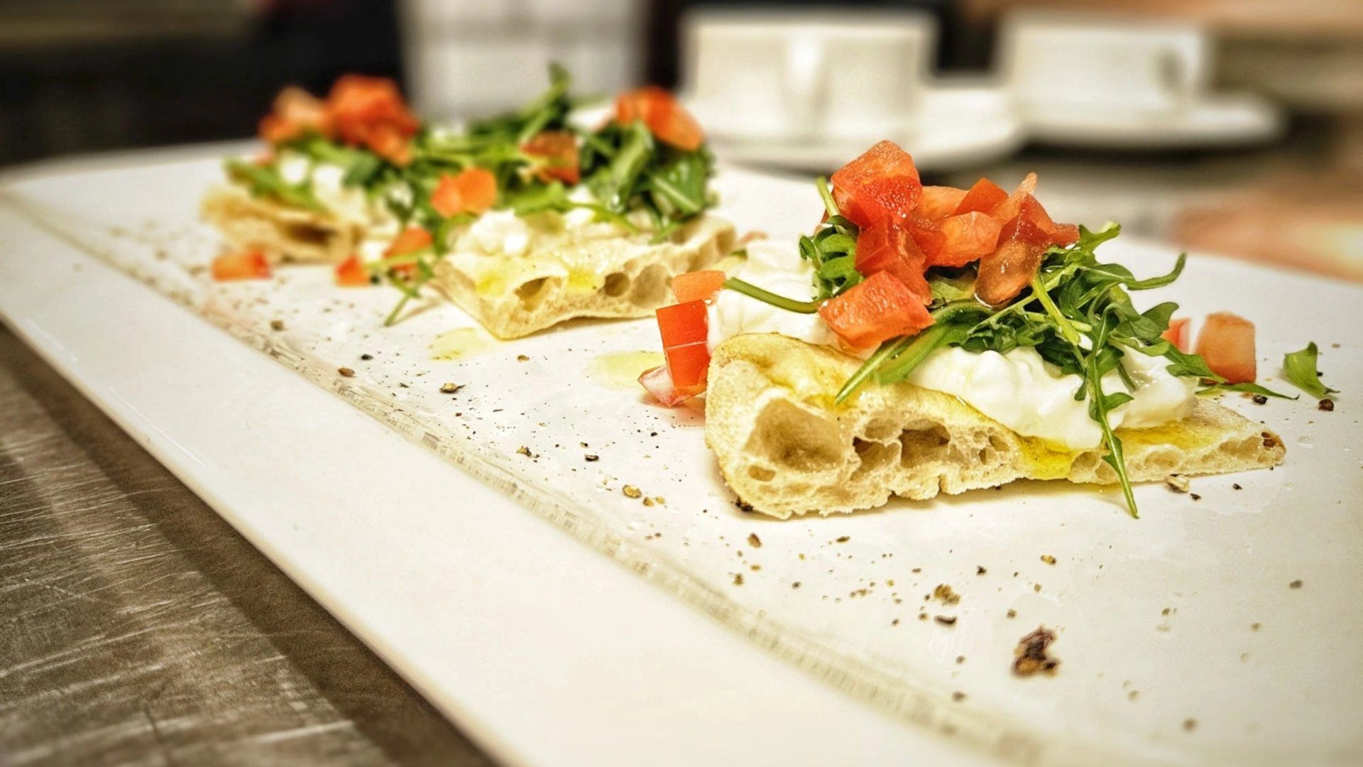 Il nostro hotel a 3 stelle in Val Gardena e la sua cucina Tre fette di pizza con rucola, formaggio fresco e pomodoro su piatto bianco