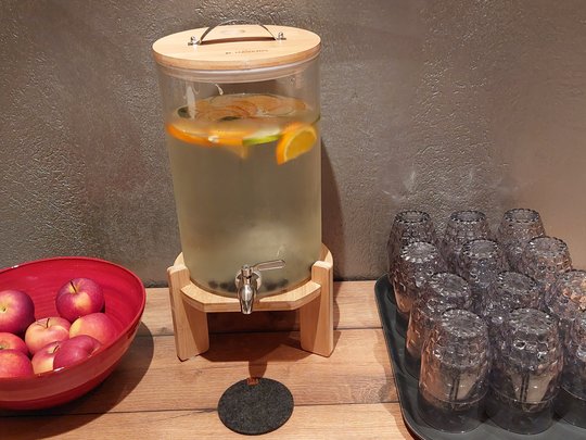 Hotel a Santa Cristina in Val Gardena con piscina: relax puro Distributore d'acqua con frutta, mele rosse in ciotola e bicchieri rovesciati su tavolo