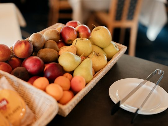 Il nostro hotel a 3 stelle in Val Gardena e la sua cucina Cesto con diversi frutti accanto a un piatto e pinze