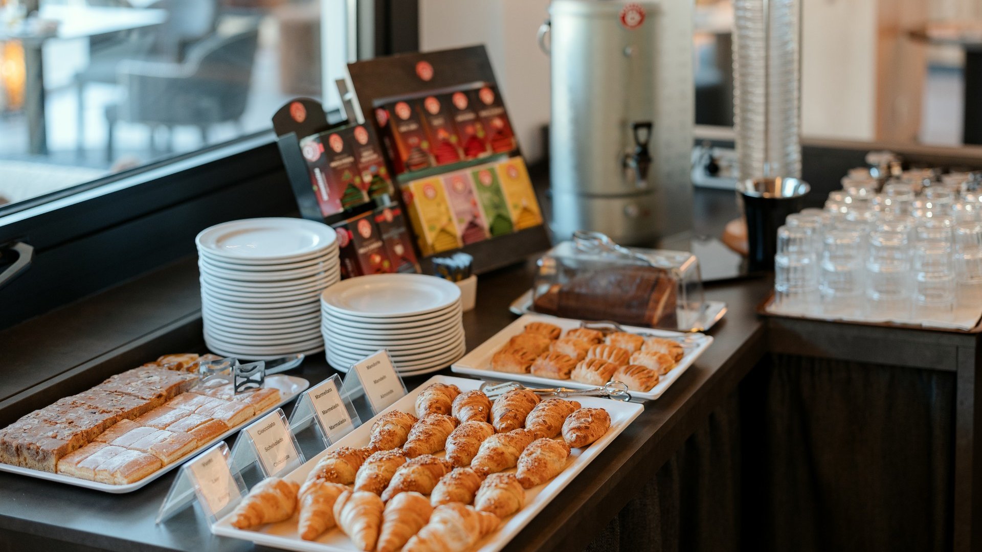 Il nostro hotel a 3 stelle in Val Gardena e la sua cucina Buffet con croissant, dolci, bustine di tè, bicchieri e piatti