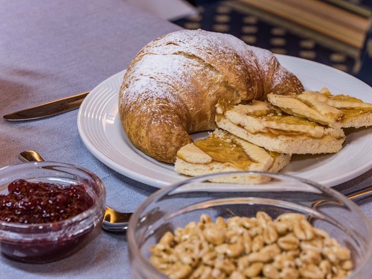 Deine Unterkunft in St. Christina im Grödnertal: Willkommen! Croissant, Kekse, Marmelade und Frühstückszerealien auf einem gedeckten Tisch