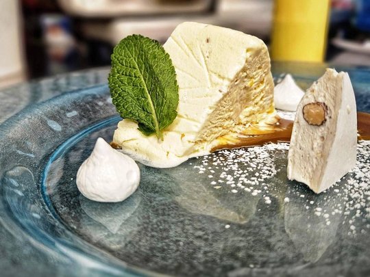Il nostro hotel a 3 stelle in Val Gardena e la sua cucina Dessert cremoso con foglia di menta e zucchero a velo su piatto di vetro