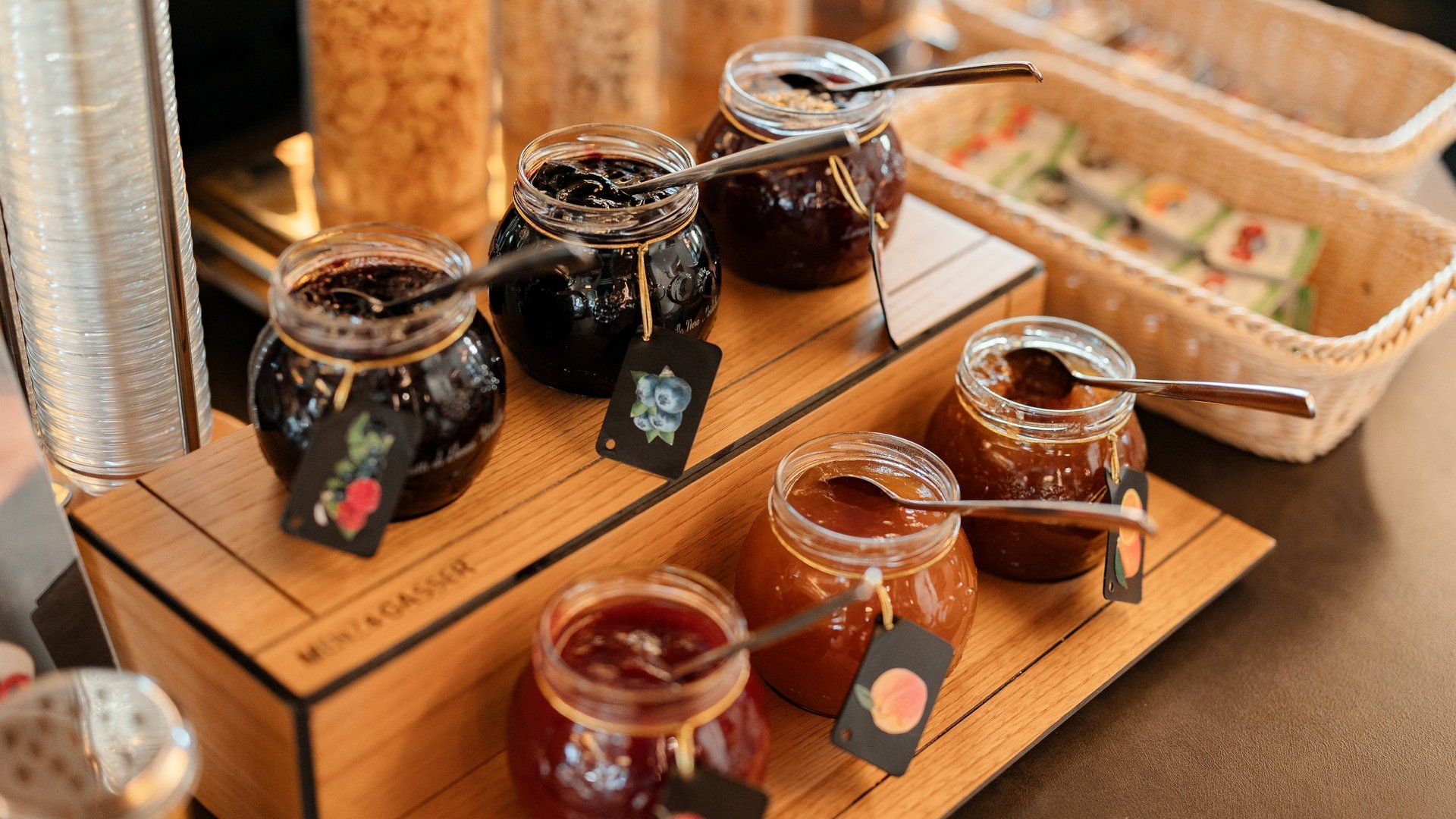 Il nostro hotel a 3 stelle in Val Gardena e la sua cucina Marmellate assortite in barattoli con cucchiai su supporto di legno