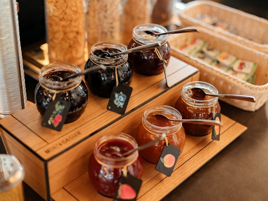 Il nostro hotel a 3 stelle in Val Gardena e la sua cucina Marmellate assortite in barattoli con cucchiai su supporto di legno