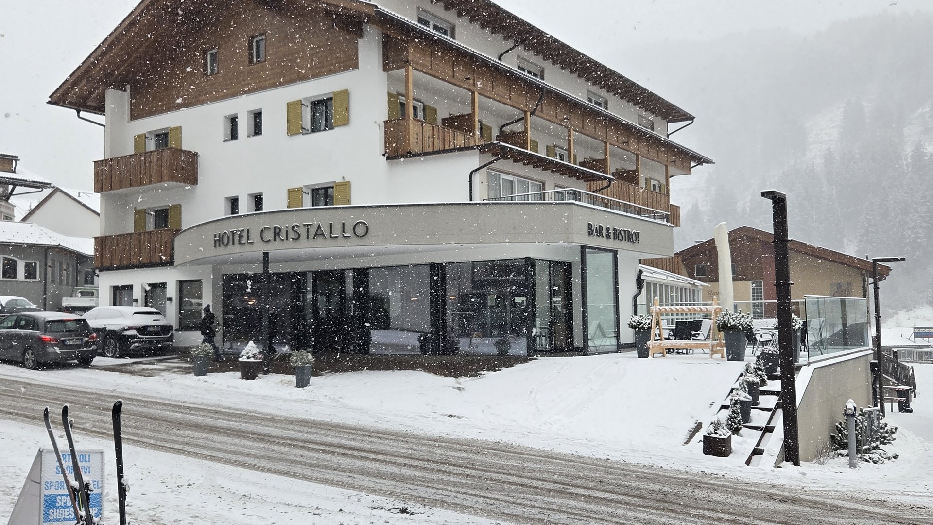 Deine Unterkunft in St. Christina im Grödnertal: Willkommen! Hotel Cristallo mit Schnee und Skiern vor dem Eingang im Winter