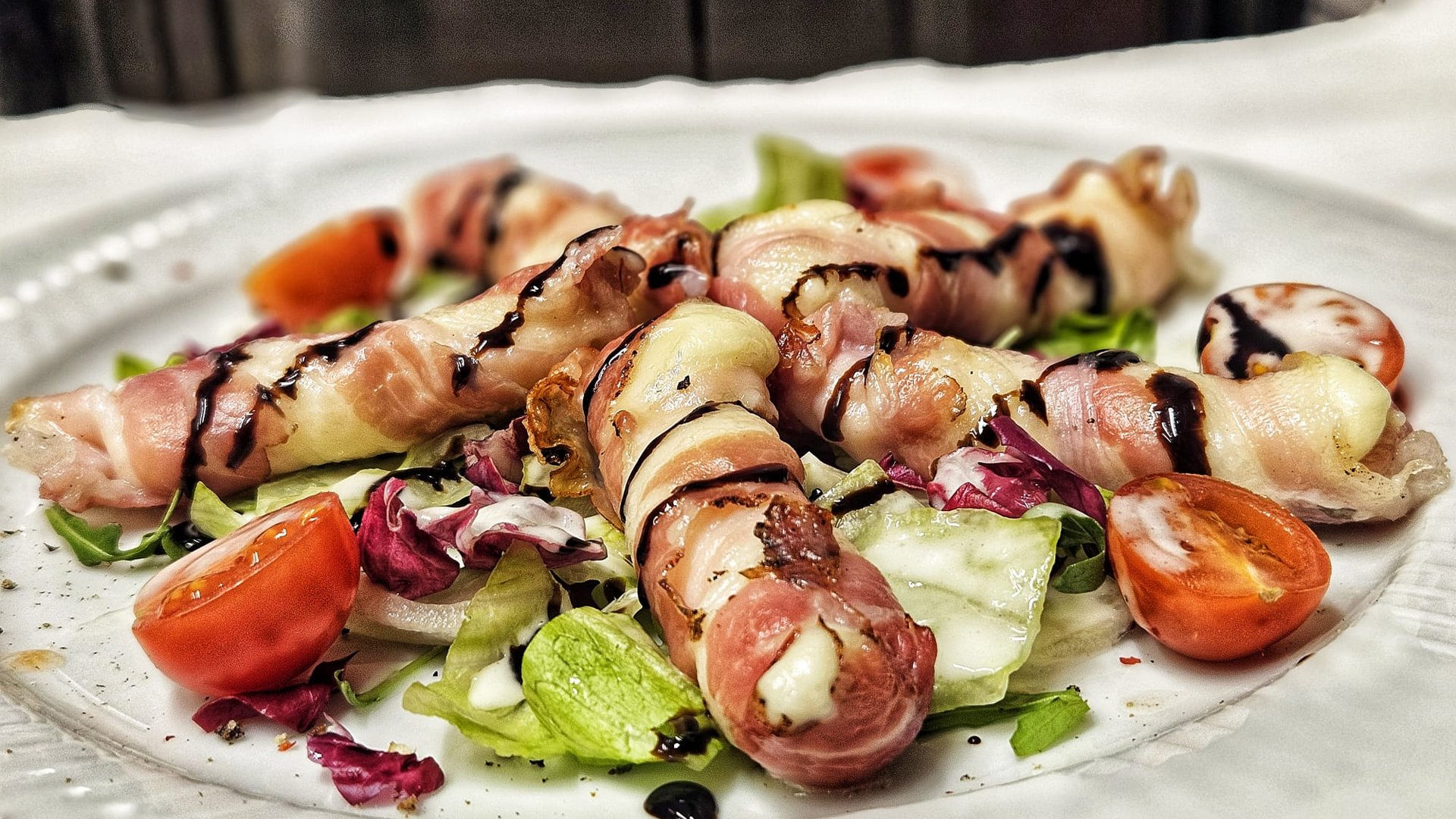 Il nostro hotel a 3 stelle in Val Gardena e la sua cucina Rotoli di formaggio avvolti nel bacon su insalata con pomodorini e balsamico