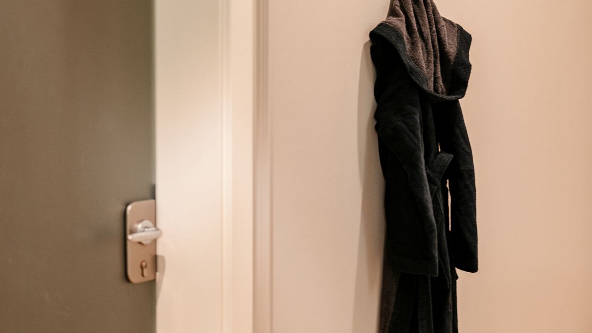 Hotel a Santa Cristina in Val Gardena con piscina: relax puro Accappatoio nero appeso a ganci a muro accanto a porta chiusa