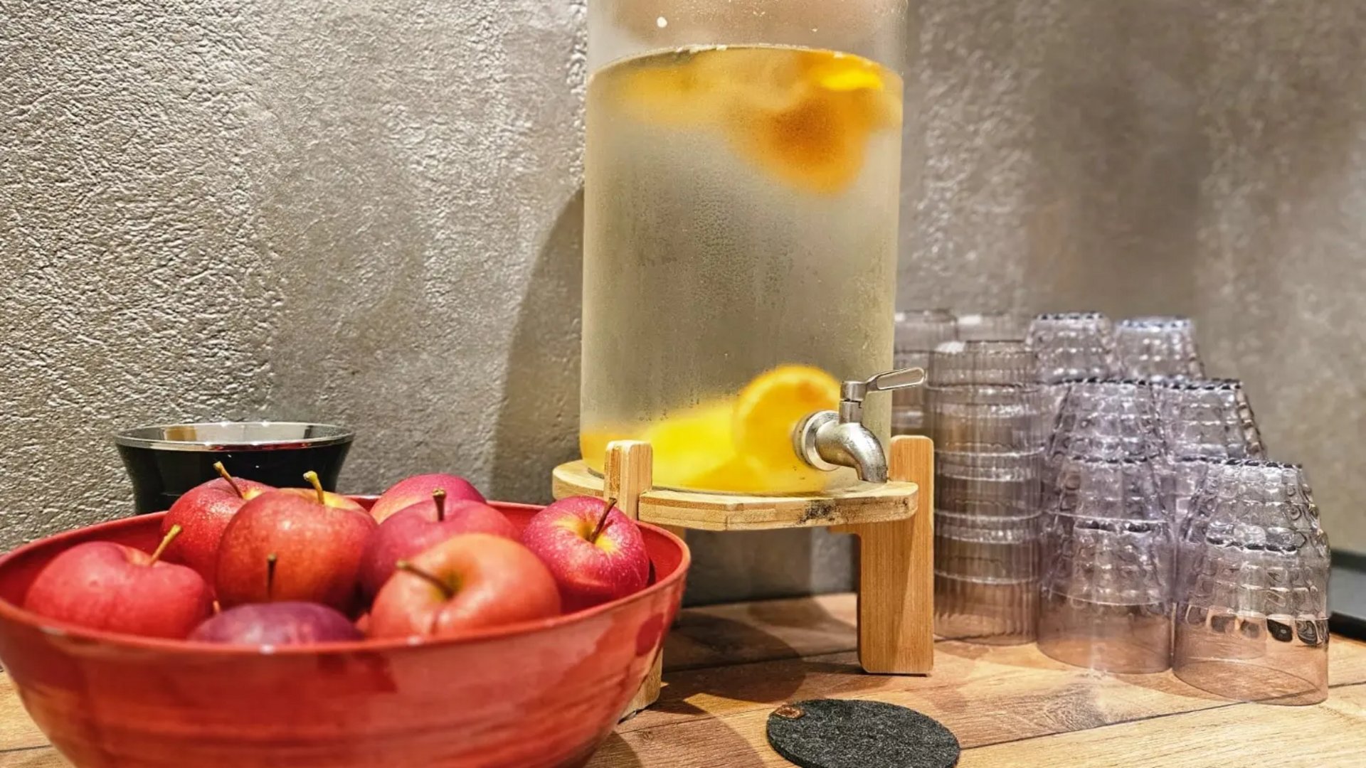 Hotel a Santa Cristina in Val Gardena con piscina: relax puro Ciotola rossa con mele accanto a dispenser d'acqua e bicchieri impilati