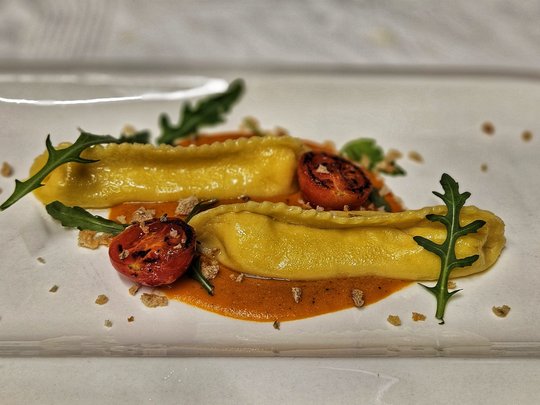 Il nostro hotel a 3 stelle in Val Gardena e la sua cucina Due ravioli su salsa con pomodoro grigliato e rucola su piatto bianco
