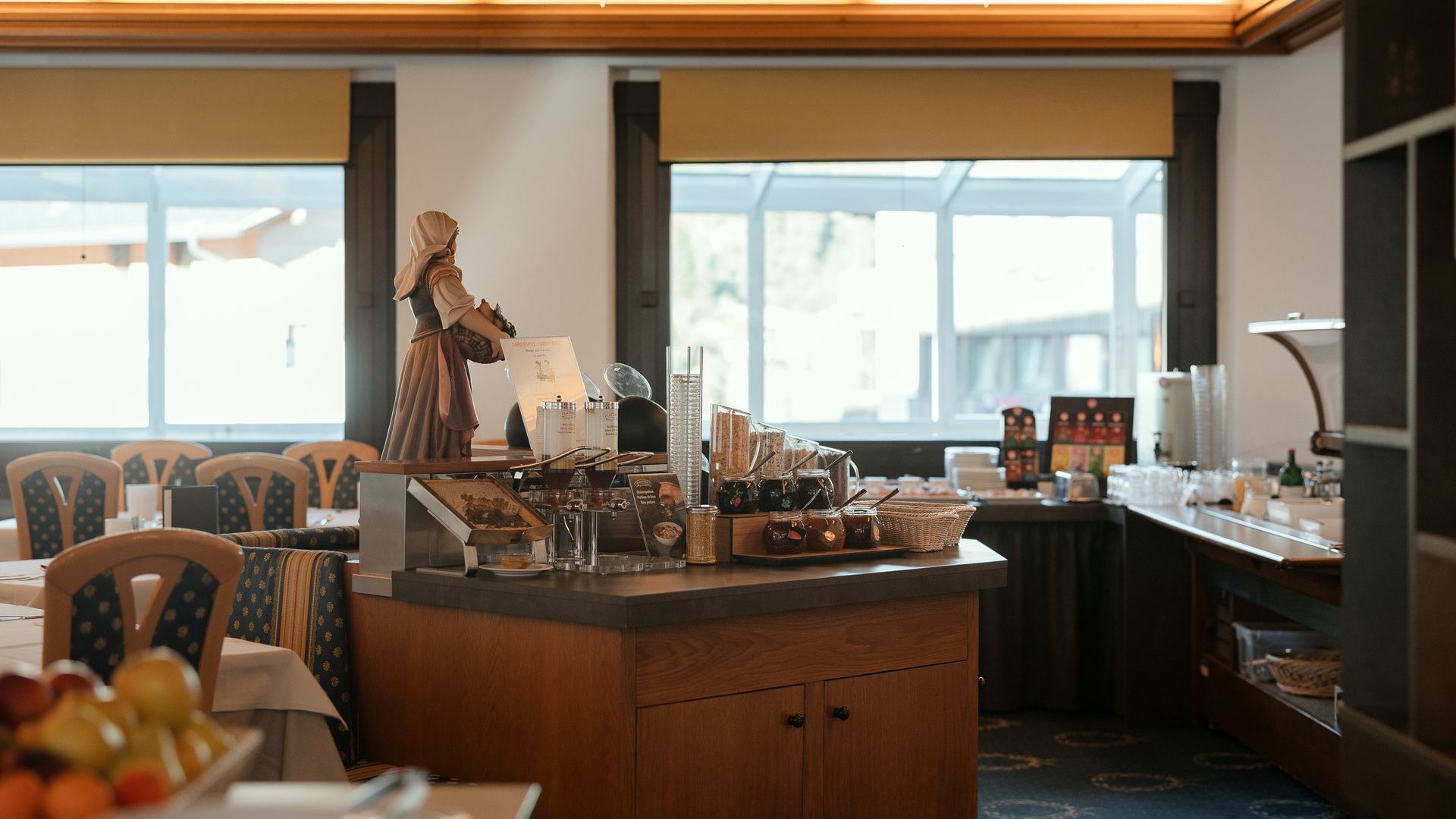 Il nostro hotel a 3 stelle in Val Gardena e la sua cucina Interno di un buffet per la colazione accogliente con decorazioni in legno e statue